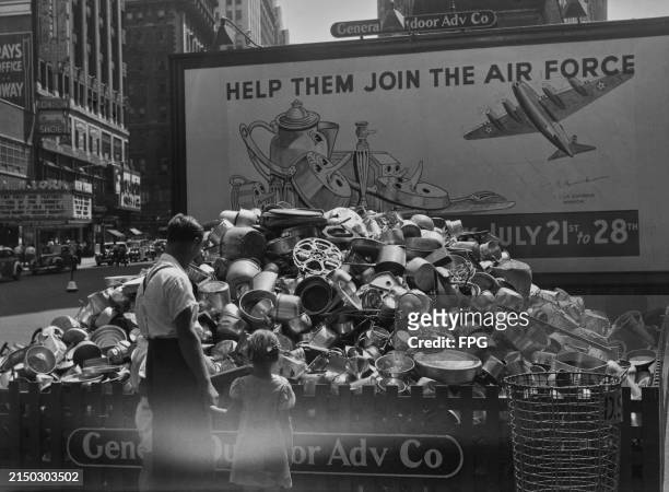 Pile of scrap aluminium beneath a billboard reading 'Help them join the air force', featuring an image of anthropomorphic metal objects looking at an...