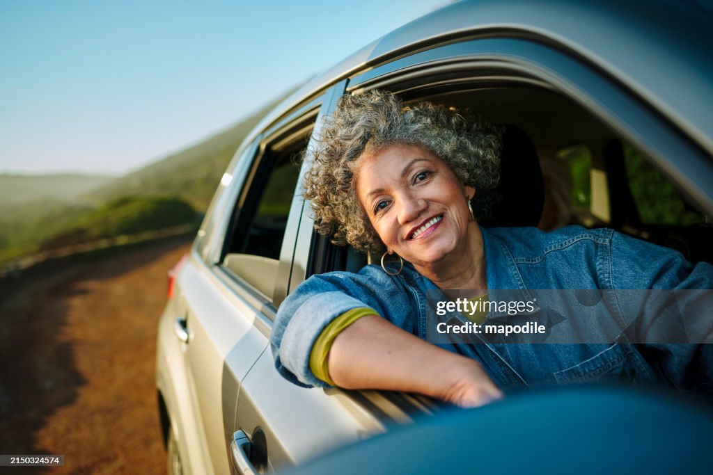 Reife Frau lächelt, während sie während einer Autofahrt aus dem Autofenster schaut