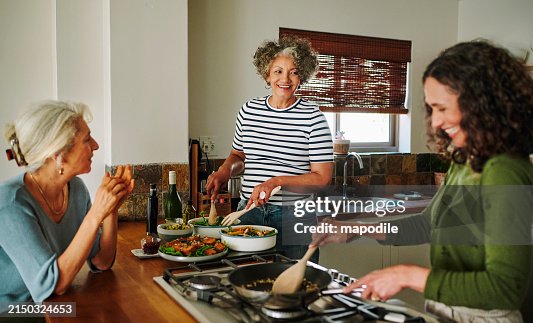 Mature women laughing while cooking together in the kitchen of their vacation rental Mature women laughing while cooking together in the kitchen of their vacation rental