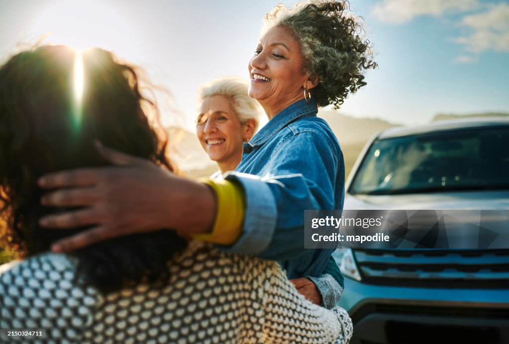 Lächelnde reife Frauen, die während eines Roadtrips an einer malerischen Küste zusammenstehen
