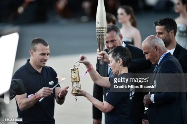 The Olympic flame is moved over to a lantern during the Olympic flame handover ceremony for the Paris 2024 Summer Olympics at Panathenaic Stadium on...