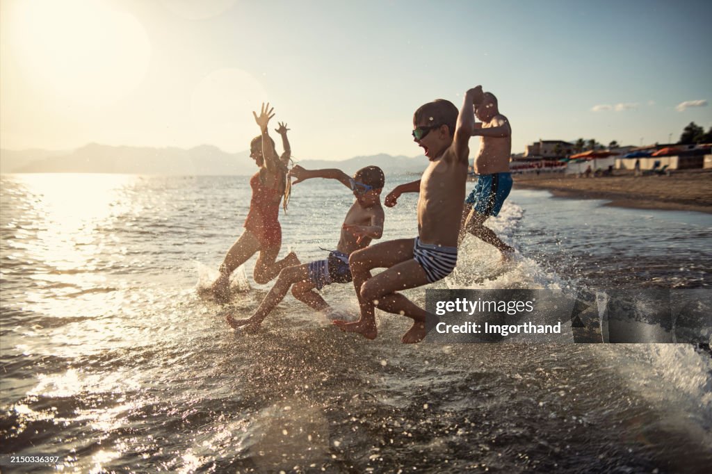 Senior man running and jumping to the sea with grandchildren