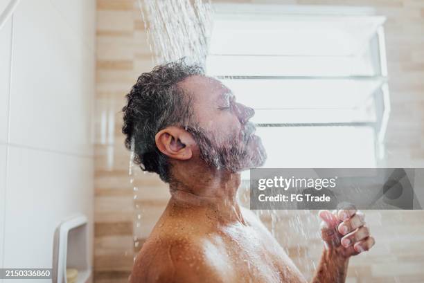 mature man taking a shower in the bathroom - douche stockfoto's en -beelden