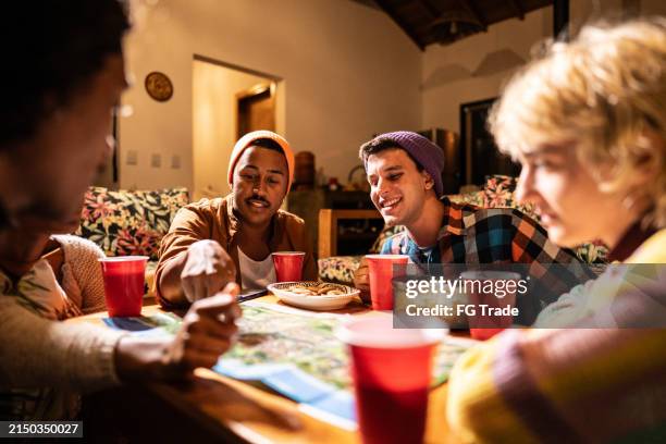 friends playing board games on living room at home - bordspel stockfoto's en -beelden