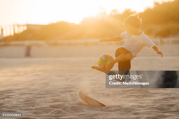 teenage boy doing some performance with ball on the beach - kicking sand stock pictures, royalty-free photos & images