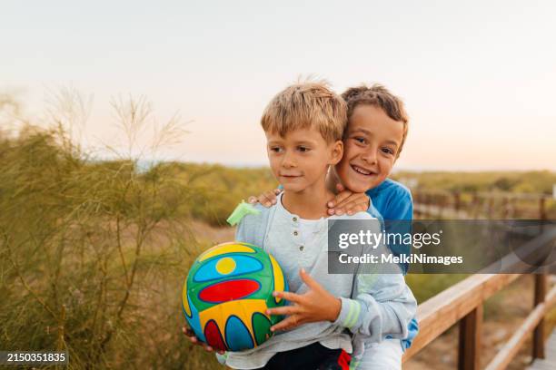 two boys having so much fun on their summer vacation playing with ball at the beach - kicking sand stock pictures, royalty-free photos & images