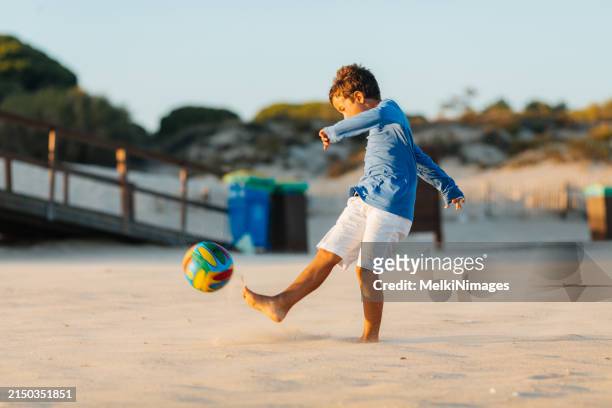 boy having so much fun on his summer vacation playing with ball at the beach - kicking sand stock pictures, royalty-free photos & images