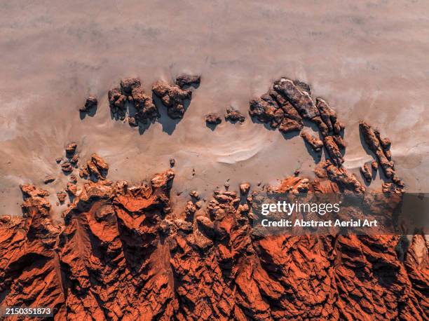 top-down drone photograph showing sandstone cliffs at the edge of a beach, james price point, the kimberley, western australia, australia - crevice stock pictures, royalty-free photos & images