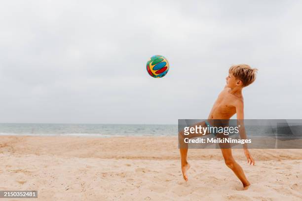 teenage boy doing some performance with ball on the beach - kicking sand stock pictures, royalty-free photos & images