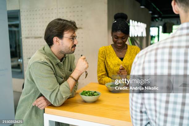 i colleghi fanno felicemente la pausa pranzo, condividono sorrisi e mangiano sano insieme. - pausa pranzo foto e immagini stock