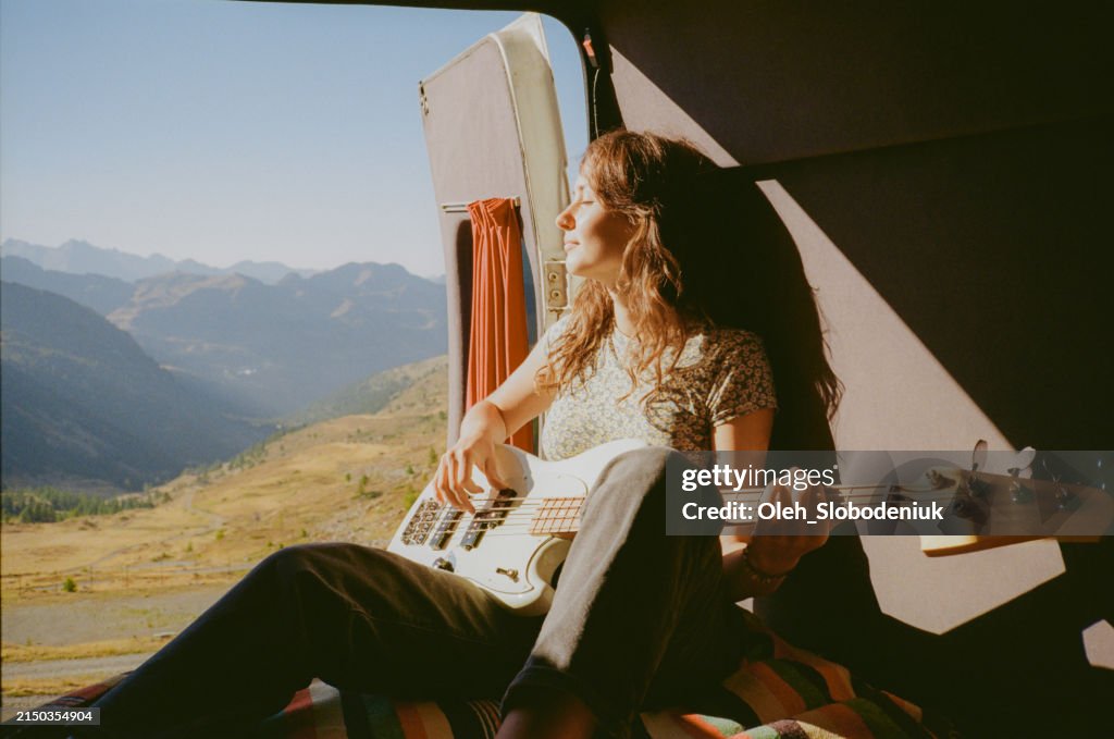 Donna con chitarra in camper in montagna