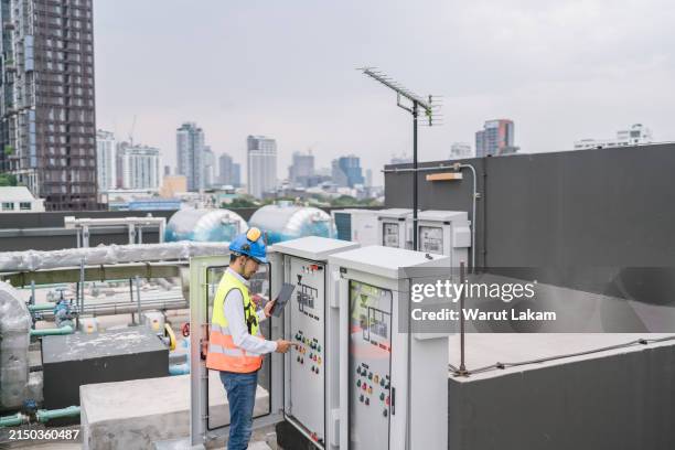 engineer or technician working with a control panel or electrical cabinet while using a tablet - rooftop hvac stock pictures, royalty-free photos & images