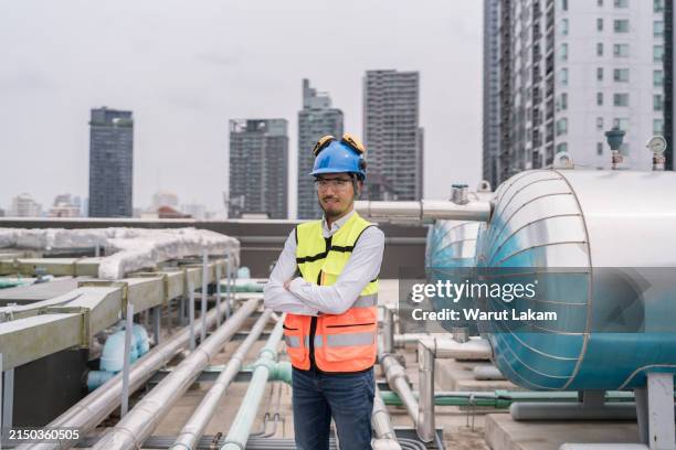 confident engineer stands with industrial tanks, symbolizing technological oversight and safety. - compresor de aire fotografías e imágenes de stock