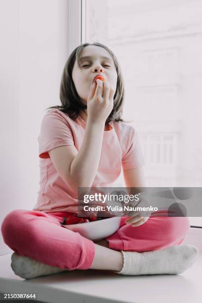 a cute little girl eats strawberries. homely atmosphere. - geschmacksknospe stock-fotos und bilder