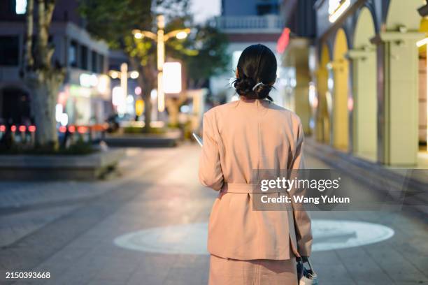the back of young business woman walking on a commercial street at night - disappointment stock pictures, royalty-free photos & images