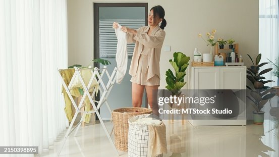 Beautiful young Asian woman drying clothes on the clothesline after washing at home. Activity of daily living at house. Beautiful young Asian woman drying clothes on the clothesline after washing at home. Activity of daily living at house.