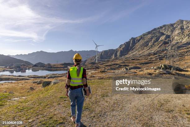 une ingénieure effectuant une inspection de l’infrastructure des éoliennes pour la production d’énergie renouvelable, utilisation d’une tablette numérique pour enregistrer les données sur place - action climatique photos et images de collection
