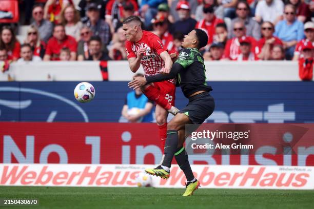 Roland Sallai of SC Freiburg tackles Aster Vranckx of VfL Wolfsburg during the Bundesliga match between Sport-Club Freiburg and VfL Wolfsburg at...