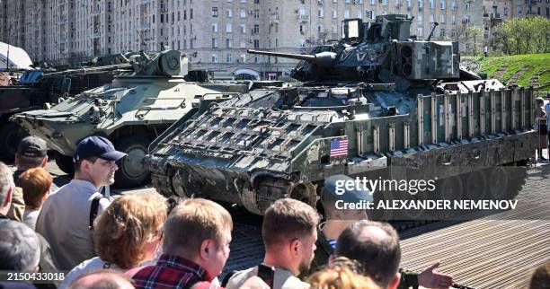 People look at a US M2A2 Bradley APC captured by Russian forces in Ukraine, displayed at the WWII memorial complex at Poklonnya Hill western in...