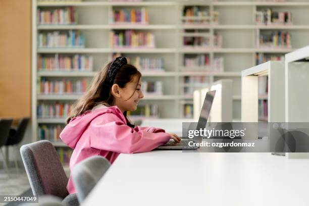 little girl studying on laptop in the library - turkey school stock pictures, royalty-free photos & images
