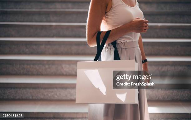 elegant woman in stylish outfit holding shopping bag on stairs - shopping bag stock pictures, royalty-free photos & images