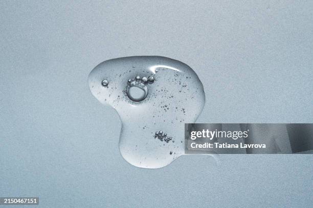 drop of transparent face serum with air bubbles on light blue background. peeling, gel for cleaning. beauty product with vitamins, ceramides, hyaluronic acid, essential oil, cbd, retinol, collagen. - face serum stock pictures, royalty-free photos & images