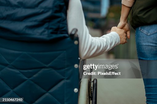 Handicapped Man in Wheelchair and Woman Holding Hands Handicapped Man in Wheelchair and Woman Holding Hands