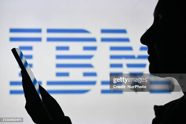 An image of a woman holding a laptop in front of an IBM logo displayed on a computer screen, on April 29 in Edmonton, Canada.