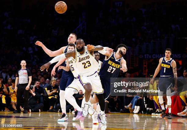 LeBron James of the Los Angeles Lakers steals the ball in front of Nikola Jokic and Jamal Murray of the Denver Nuggets in the second half during game...