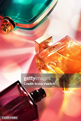 Make-up Cosmetic products for a women and men - set of Perfumes in glass bottles with caustic Light effect on Pink Color background with shadow from sunlight. Make-up Cosmetic products for a women and men - set of Perfumes in glass bottles with caustic Light effect on Pink Color background with shadow from sunlight.