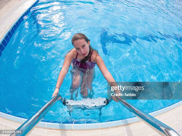 girl on ladder getting out of inground pool smiling - kid reaction portrait stock pictures, royalty-free photos & images