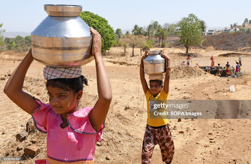 Young girls carry water in vessels near Vihigaon village,...