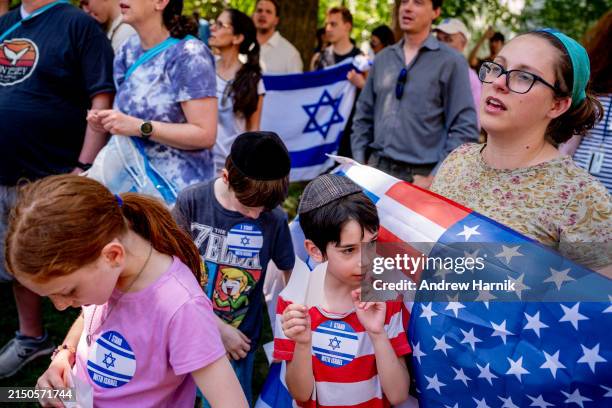 Bethany Mandel of Silver Spring, Maryland holds an American and Israeli flag and stands with her children as the Israeli national anthem is sung...