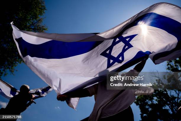 Michal Rokah of Falls Church, Virginia and Israeli Matan Showstack of Washington, DC dance and wave large Israeli flags during a rally against campus...