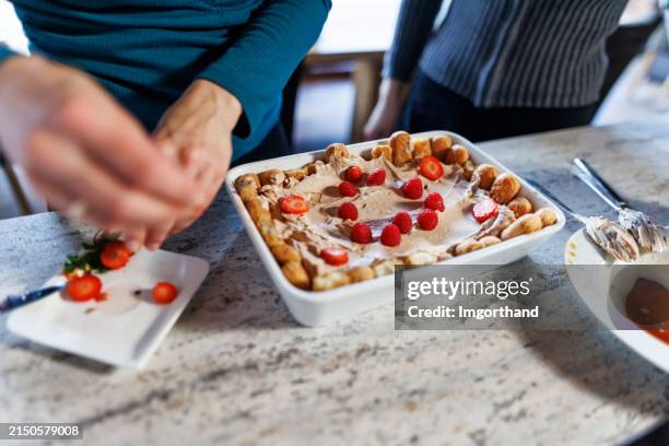 reife frau bereitet tiramisu-dessert zu - kuchenboden stock-fotos und bilder