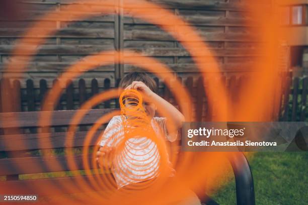 boy looking through spring toy outdoors - nieuwsgierigheid stockfoto's en -beelden