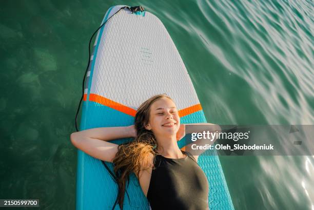 portrait of teenage  girl sup boarding on mediterranean coast in summer - kid reaction portrait stock pictures, royalty-free photos & images
