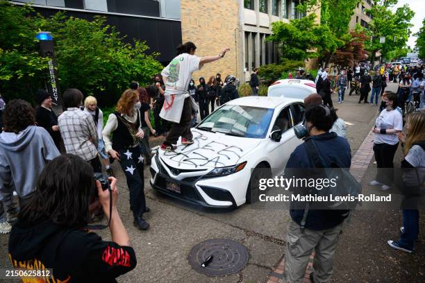 Protesters deface a car after a counter-protester drove towards the crowd gathered at the Portland State University campus, exited their vehicle and...