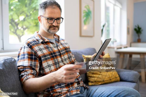 man typing his social security number over a digital tablet from home - sozialversicherung stock-fotos und bilder