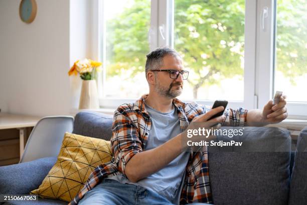 man typing his social security number over a mobile phone from home - social security kaart stockfoto's en -beelden