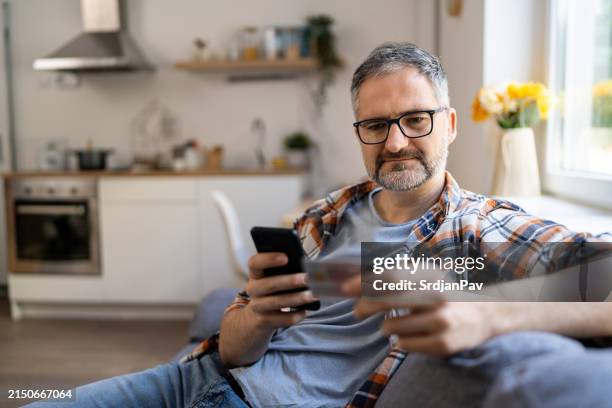 homem digitando seu cpf em um celular de casa - só homens maduros - fotografias e filmes do acervo