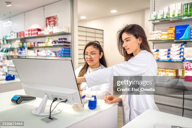 dos farmacéuticos usando la computadora en el mostrador - farmacia fotografías e imágenes de stock