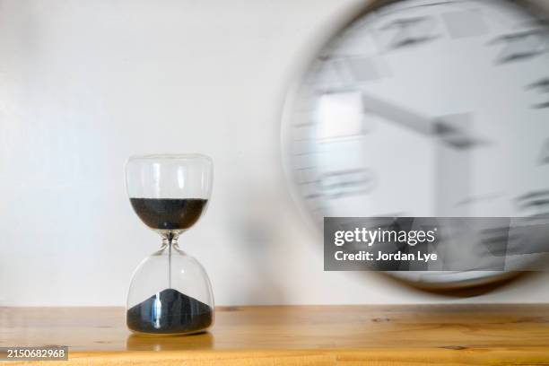 black sand clock with a vintage wall clock in motion - relógio de parede imagens e fotografias de stock