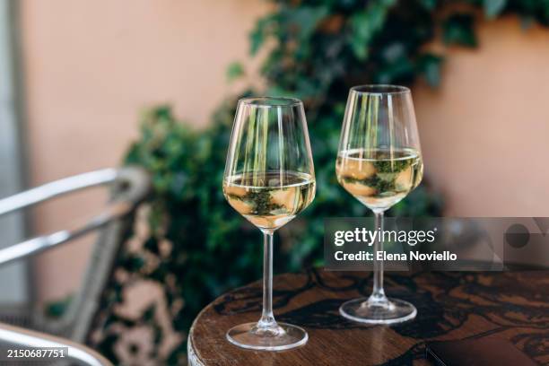 two glasses of white wine or prosecco on a table in a bar on the street in a european city, aperitif time - prosecco glas stock-fotos und bilder