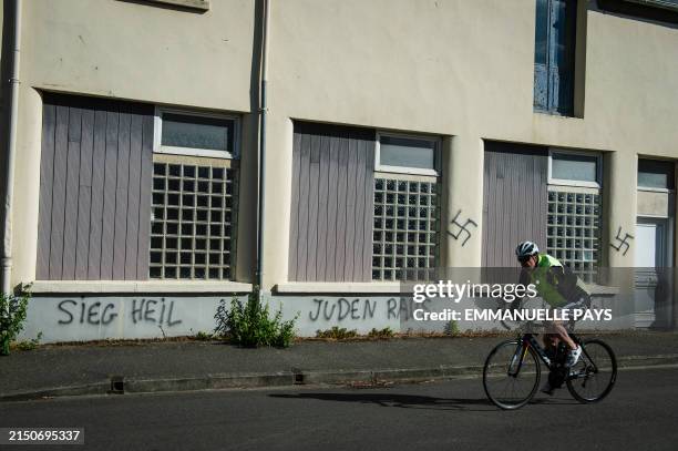 Cyclist passes Nazi and anti-Semitic tags, including swastikas, on the facade of a Masonic lodge, Plerin, France, May 2, 2024.