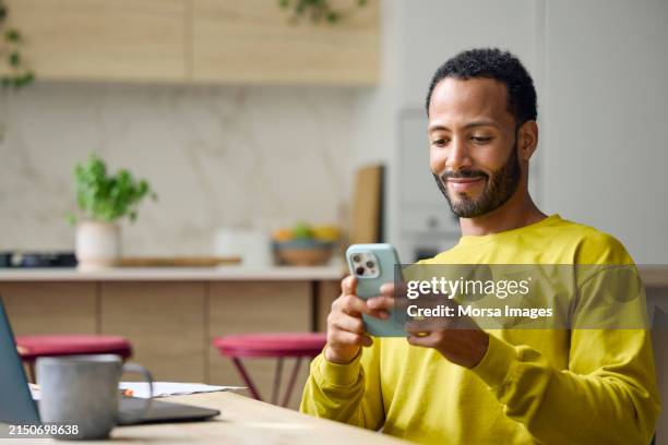 freelancer using smart phone while working from home - telephone photos et images de collection