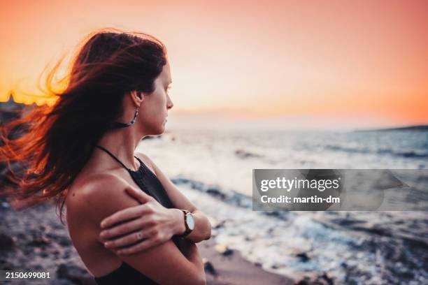 donna in riva al mare che fissa il tramonto - guardare fisso foto e immagini stock