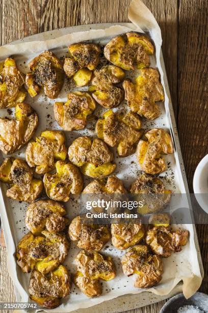 crispy smashed new potatoes with dried herbs and sea salt in baking tray - kartoffelgericht stock-fotos und bilder