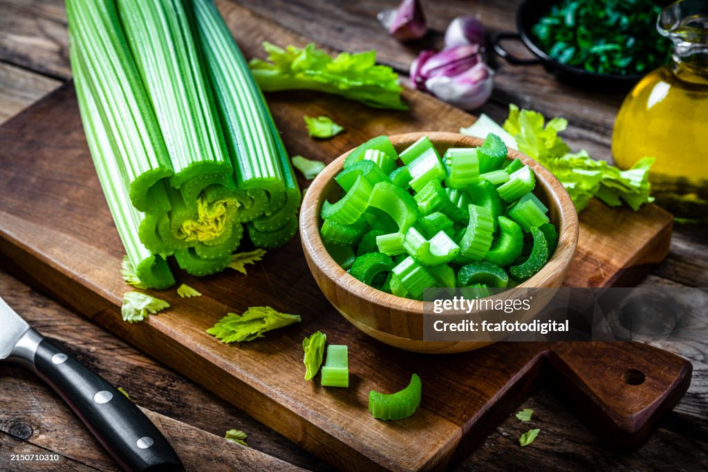 Wooden bowl filled with fresh organic chopped celery.