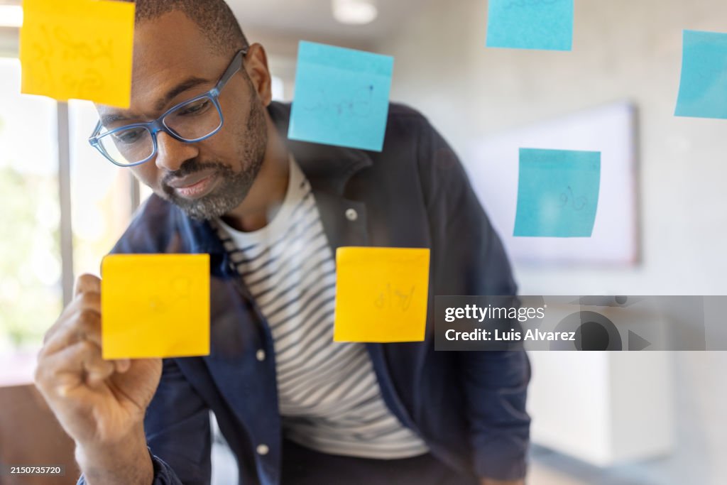 Startup entrepreneur brainstorming ideas using sticky notes on a transparent board
